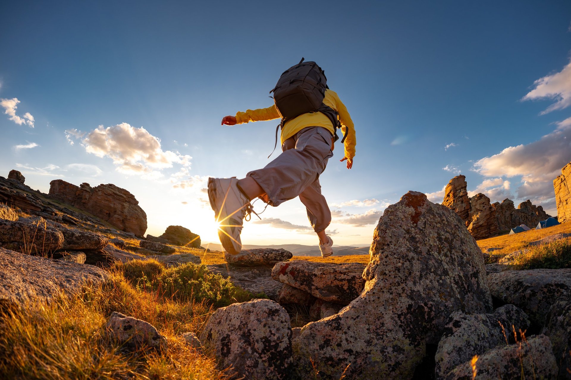 Wanderin springt über Felsen bei Sonnenuntergang – Norwegen Abenteuer