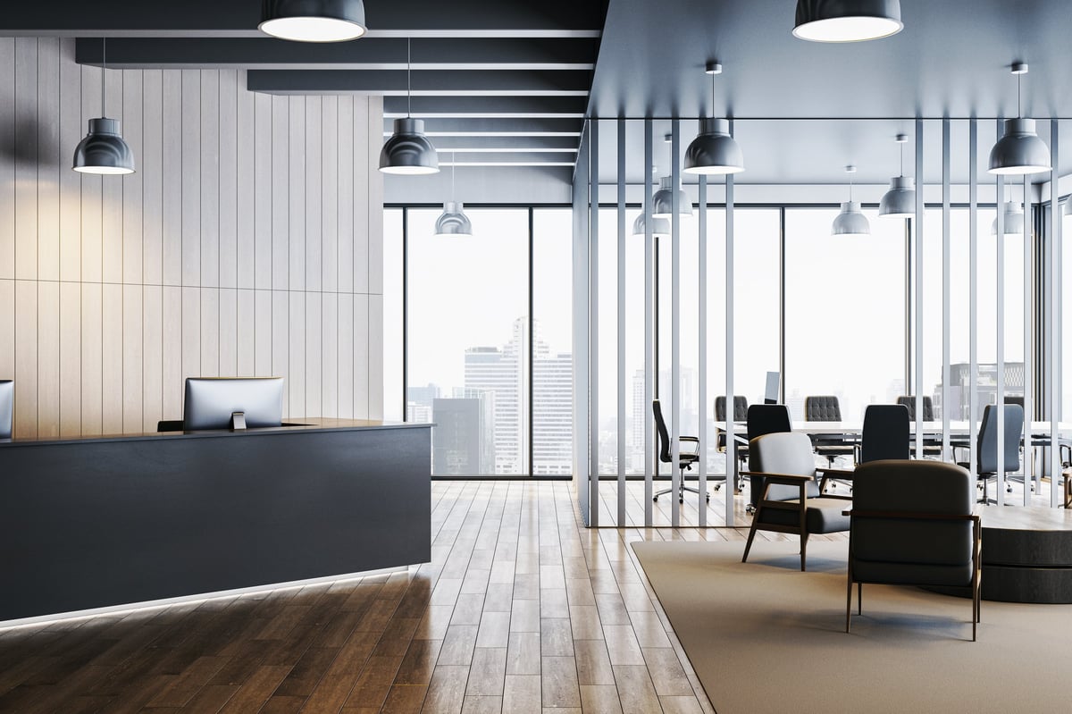Contemporary office interior with sleek desk, lounge chairs, and conference room, featuring wood flooring and cityscape background