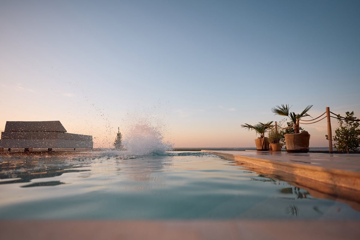 Water splash from a jump into infinity pool at summer sunset
